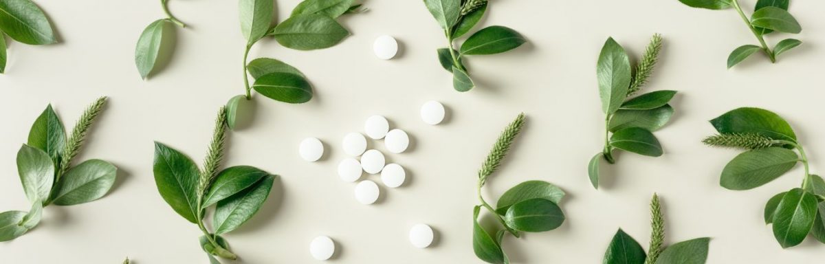 Round, white pills surrounded by green plants.