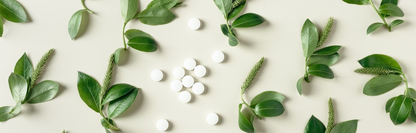 Round, white pills surrounded by green plants.