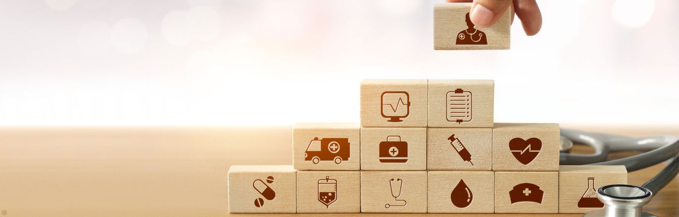 Small building blocks being stacked on top of each other. They each have small healthcare symbols on them.