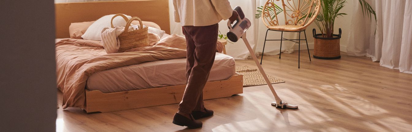 A person vacuuming their bedroom.