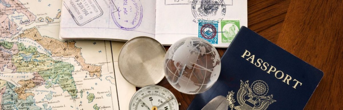 An American passport on a table with a map and various travel trinkets.