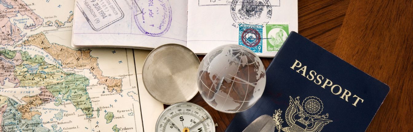An American passport on a table with a map and various travel trinkets.