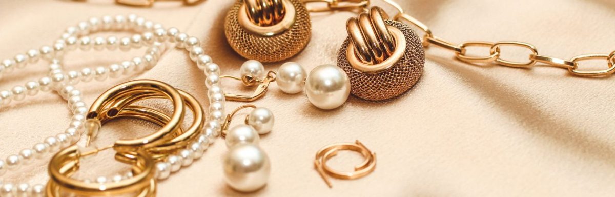 Different gold jewelry and pearl items laid out together.